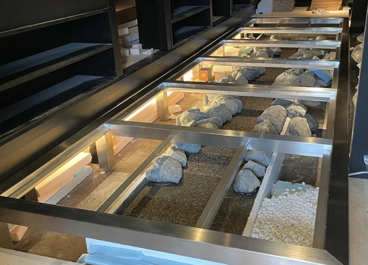 金属フレームの上に丸いガラス花器を配置したディスプレイ作品。ガラスの中には花や植物が入っている。