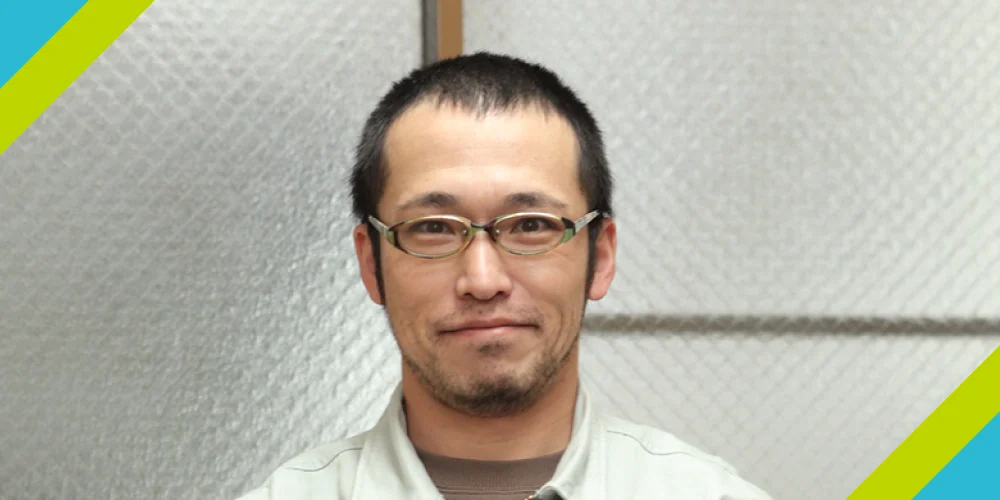 土肥板金工業の職人が溶接作業で金属のケージ状構造物を精密に加工している様子。保護手袋を着用し、丁寧なものづくりを実践する職人の姿